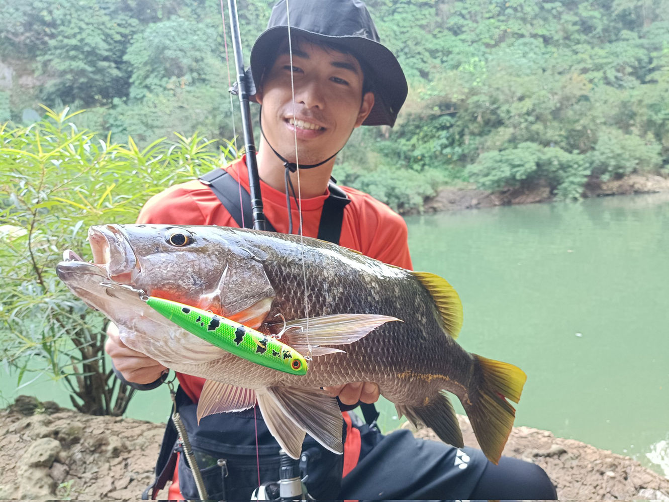 Happy angler holding a solid Papuan blackbass with a tiger pattern lure